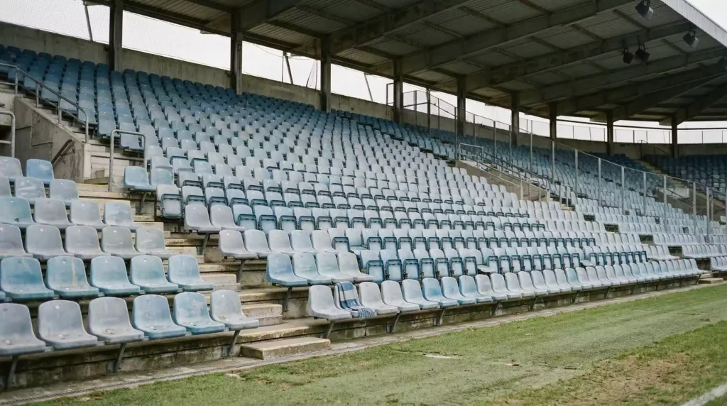 Descenso en la Premier League: grada vacía de estadio inglés con asientos desgastados y luz tenue
